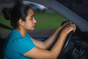 concentrated latin woman while driving her car