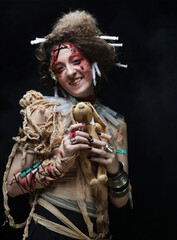 Young woman in zombie style holding a toy bunny in her hands. Bright make up and hairstyle. Party concept.