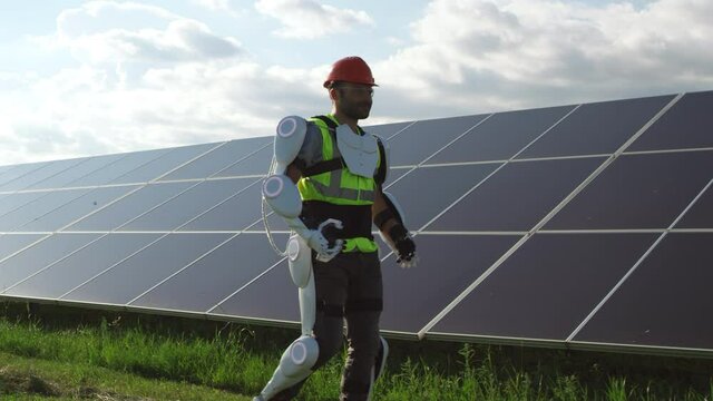 Male engineer in exoskeleton walking on solar plant