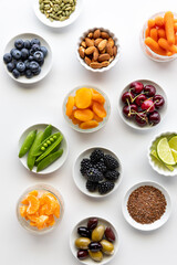 Top down view of small dishes filled with various healthy organic ingredients, against a white background.