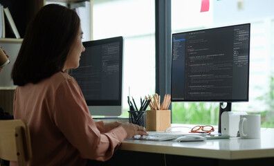 Plakat Side view of female programmer working with computer at modern office. Developing programming.