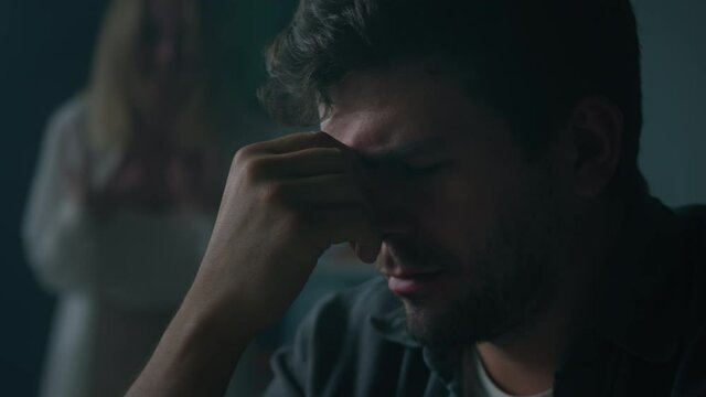 Husband holding his head while irritated emotional wife blaming and screaming. Woman shouting at man in living room at home, feeling anger and stress, bad mood. Scandals and quarrels in family.