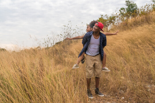 african american father and daughter ridding piggyback on mountain