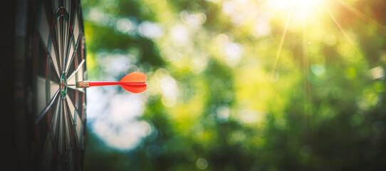 Bullseye or dart board has dart arrow throw hitting the center with bokeh nature backgrounds, shooting target for business targeting and winning goals business concepts.