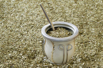 Yerba Mate calabash with yerba mate dried sticked leaves covering all the table