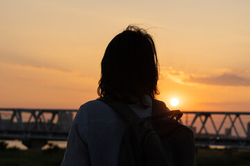 夕焼けを見つめる女性の後ろ姿