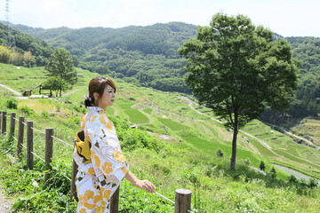 棚田を歩く浴衣姿の女性