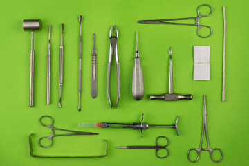 Set of dental instruments for teeth extraction with green background and top view