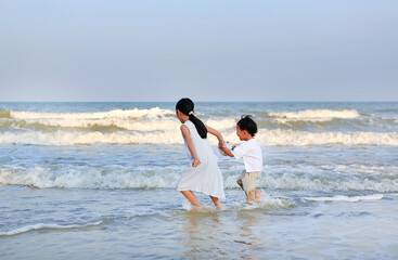 Fototapeta na wymiar Asian little kid boy and girl having fun on sea beach in summer