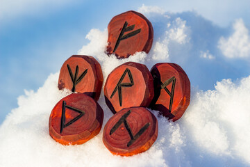 Elder Futhark. Runes of red color carved from wood in the snow