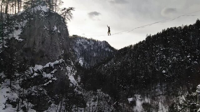 Brave Man Standing up on a Line While Highlining in a Winter Mountain Range