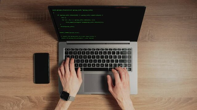Closeup a man hands are typing commands of a laptop keyboard. A man is writing a program. The developer is coding. Code on the laptop screen. Concept of programming and development web.