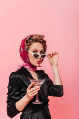 Girl with hair curlers on her head takes off glasses and looks into camera. Woman in scarf whistles...