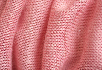 Close-up photo of pink fabric, knitting loops, threads are visible. Horizontal.