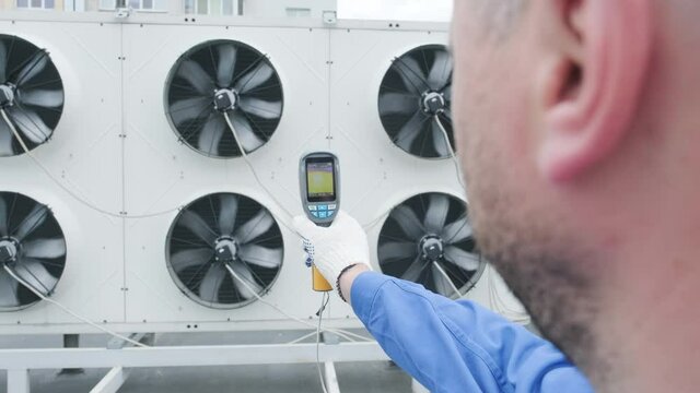 Technician uses a thermal imaging infrared thermometer to check the condensing unit heat exchanger