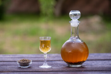 Homemade birch buds tincture in a glass bottle and a wine crystal glass on a wooden table