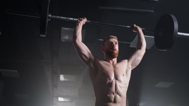 Slow motion of crossfit athlete performs clean and jerk. Young man doing the clean and jerk weightlifting exercise at the gym.