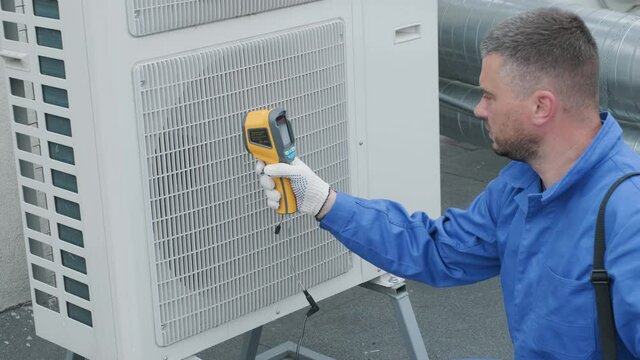 Technician uses a thermal imaging infrared thermometer to check the condensing unit heat exchanger