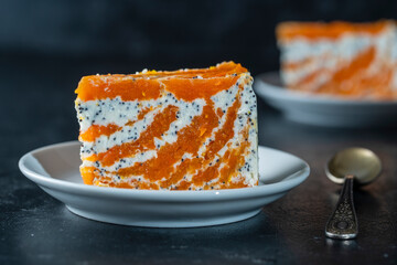 Carrot curd cake with poppy and orange in plate, close up. Cake without baking
