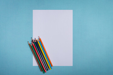 A blank white sheet and colored pencils for drawing on a plain textured background with space for copying and lettering.