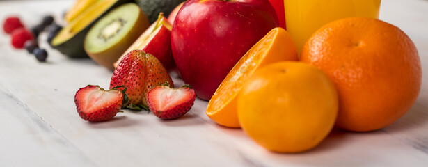 Different fruits juice in glass, apple, orange and strawberry juice with straw, looking refreshing on colourful wood board in front of white wall background. Picture decorating with fresh fruits