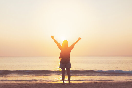 Copy space of woman rise hand up on sunset sky at beach and island background.