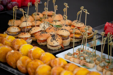 Mini burgers with black sesame seeds at the buffet table. 