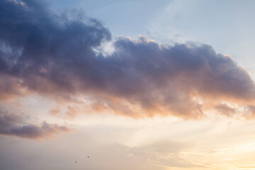 Colorful sunset or sunrise in the sky. The sky and clouds are painted in different bright orange, yellow and blue colors.