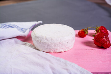 Camembert with strawberries with mint on a pink wooden board on a grey background 