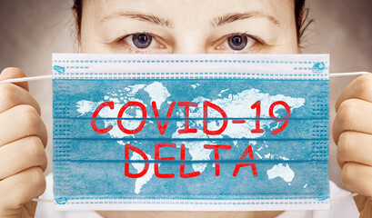Face mask in hand with inscription COVID 19 DELTA . Delta variant outbreak around the world