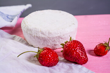 Camembert with strawberries with mint on a pink wooden board on a grey background 