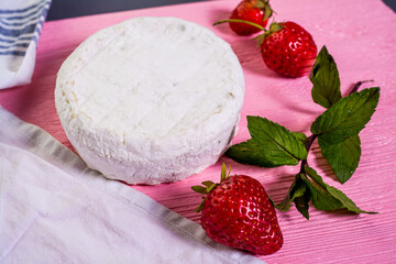 Camembert with strawberries with mint on a pink wooden board on a grey background 