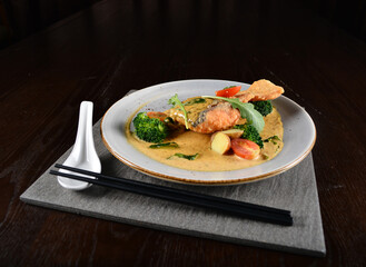 deep fried salmon fish with golden salted egg yolk sauce and vegetables seafood in dark background asian halal menu