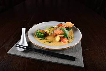 deep fried salmon fish with golden salted egg yolk sauce and vegetables seafood in dark background asian halal menu