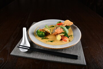 deep fried salmon fish with golden salted egg yolk sauce and vegetables seafood in dark background asian halal menu
