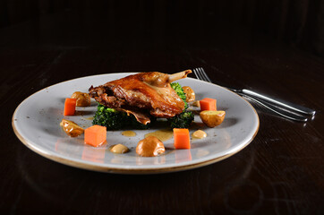 marinated grilled duck leg confit with vegetables and sauce main course in dark background western halal menu