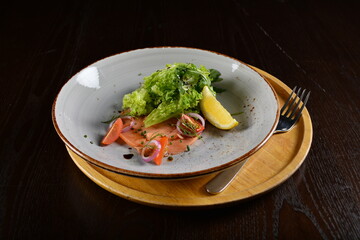 smoked salmon fish with vegetables, lemon and salad dressing appetiser in dark background western halal menu