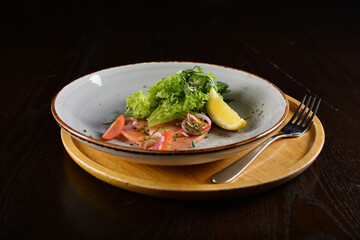 smoked salmon fish with vegetables, lemon and salad dressing appetiser in dark background western halal menu