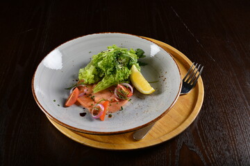 smoked salmon fish with vegetables, lemon and salad dressing appetiser in dark background western halal menu
