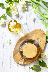 Therapeutic herbal tea. Hot Jasmine tea with jasmine flowers in a glass teapot on a rustic wooden table. Top view flat lay background.