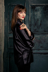 Beautiful woman with bright make up posing in Chinese costume in minimalistic interior with fan and dagger