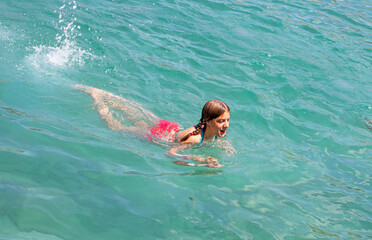 happy girl swims in a clean transparent sea, top view, horizontal.