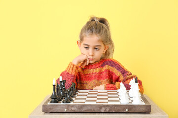 Cute little girl playing chess on color background