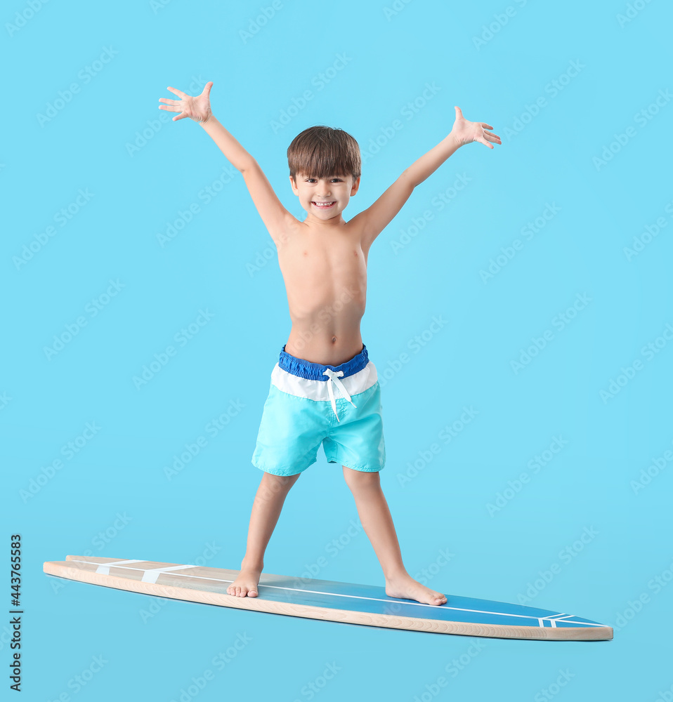 Wall mural Happy little boy with surfboard on color background