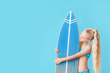 Cute little girl with surfboard on color background