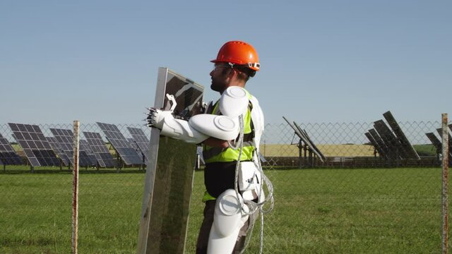 Male technician in exoskeleton carrying photovoltaic panel