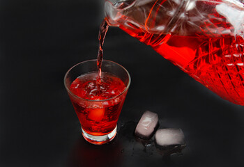 Red cherry drink in a transparent container on a black background. Summer refreshing cocktail
