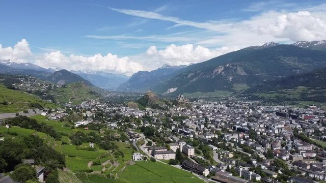 View from a drone of the beautiful city of Sion in the mountains in southern Switzerland, beautiful sunny weather with some clouds in the sky