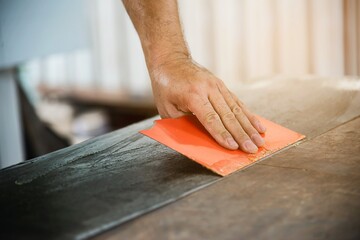 Carpenter making wooden built-in furniture putting rubber glue to attach laminate surface