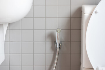 Chromium bidet shower with grey ceramic tile in toilet. silver bidet spray shower.